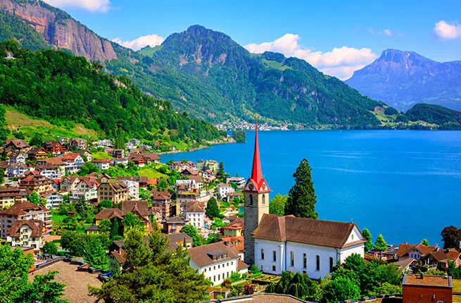 Little swiss town with gothic church on Lake Lucerne and Alps mountain, Switzerland.
